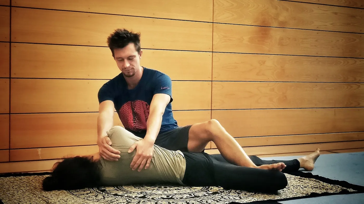Mito giving a Thai-Yoga-Massage on a mat on the floor